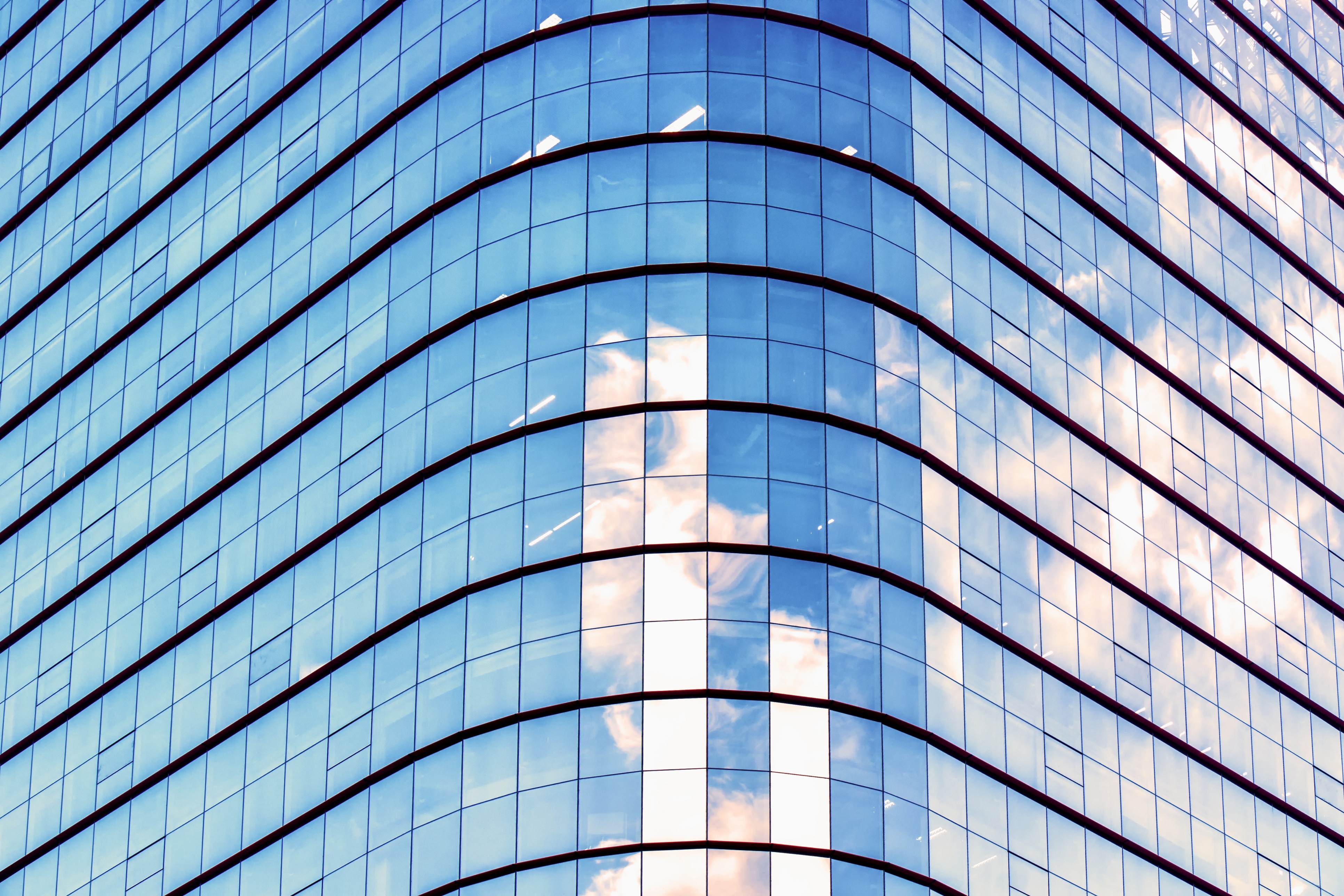 Photo of a modern building. Blue sky reflected on glass wall